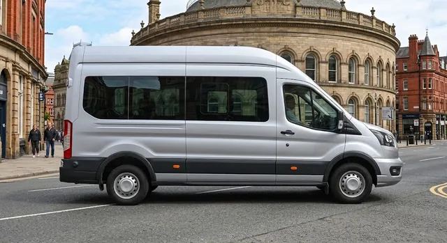 Silver high-roof minibus driving past a historic domed stone building in a city centre